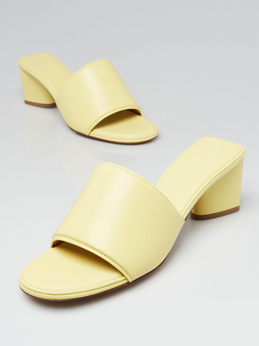 Beige high heels isolated on a yellow pastel background. Reflection of  shoes. High heels stand next